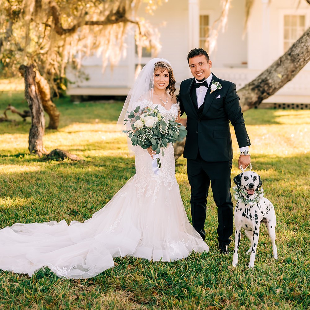 Couple and their Dalmatian on the lawn beneath a moss-draped oak, the manor house behind them